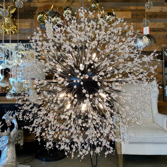 A luxurious black crystal chandelier with a starburst design, featuring matte black tubes and crystal beads, displayed in a showroom setting.