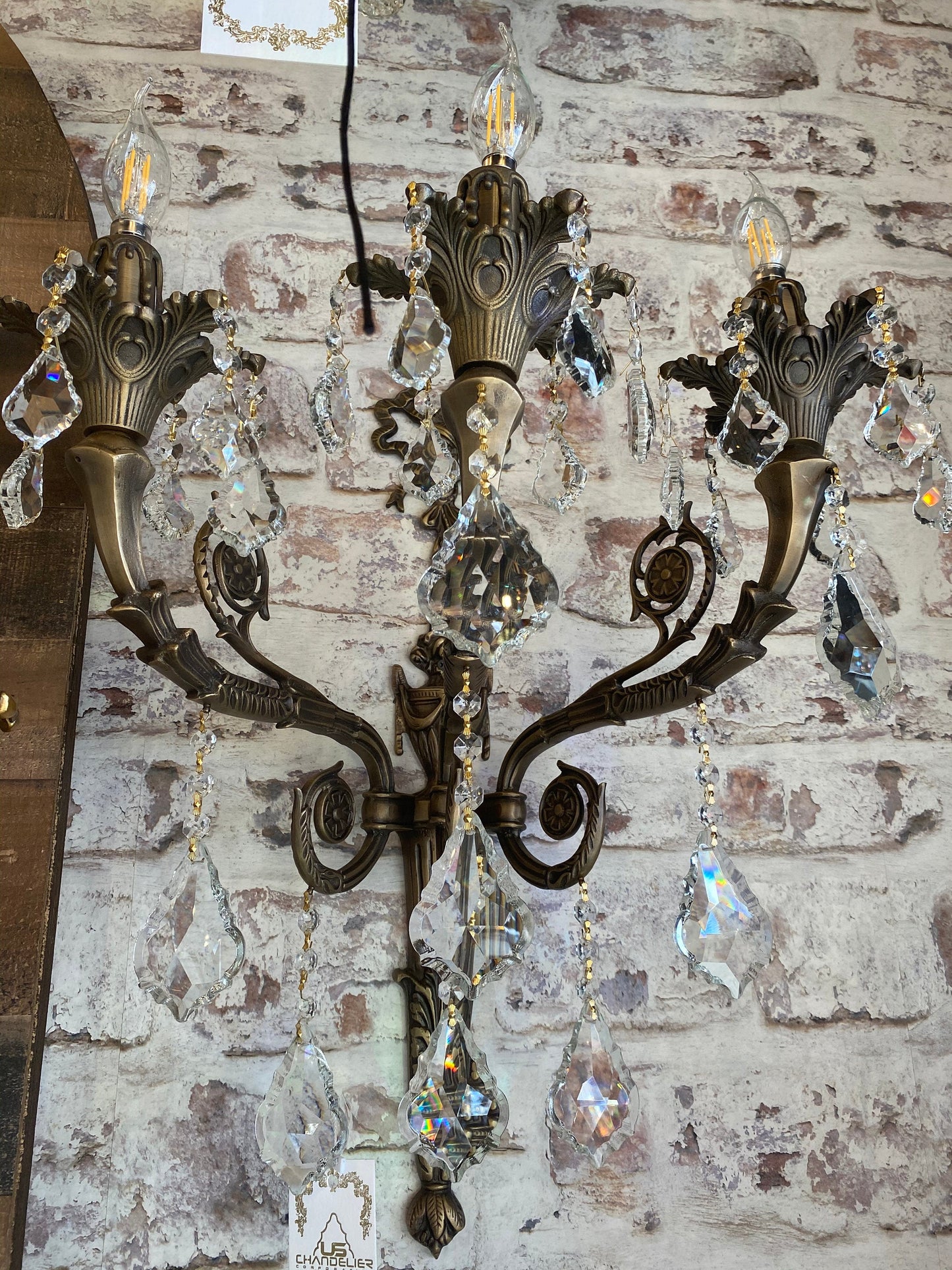 Traditional brass crystal wall sconce with three candle arms
