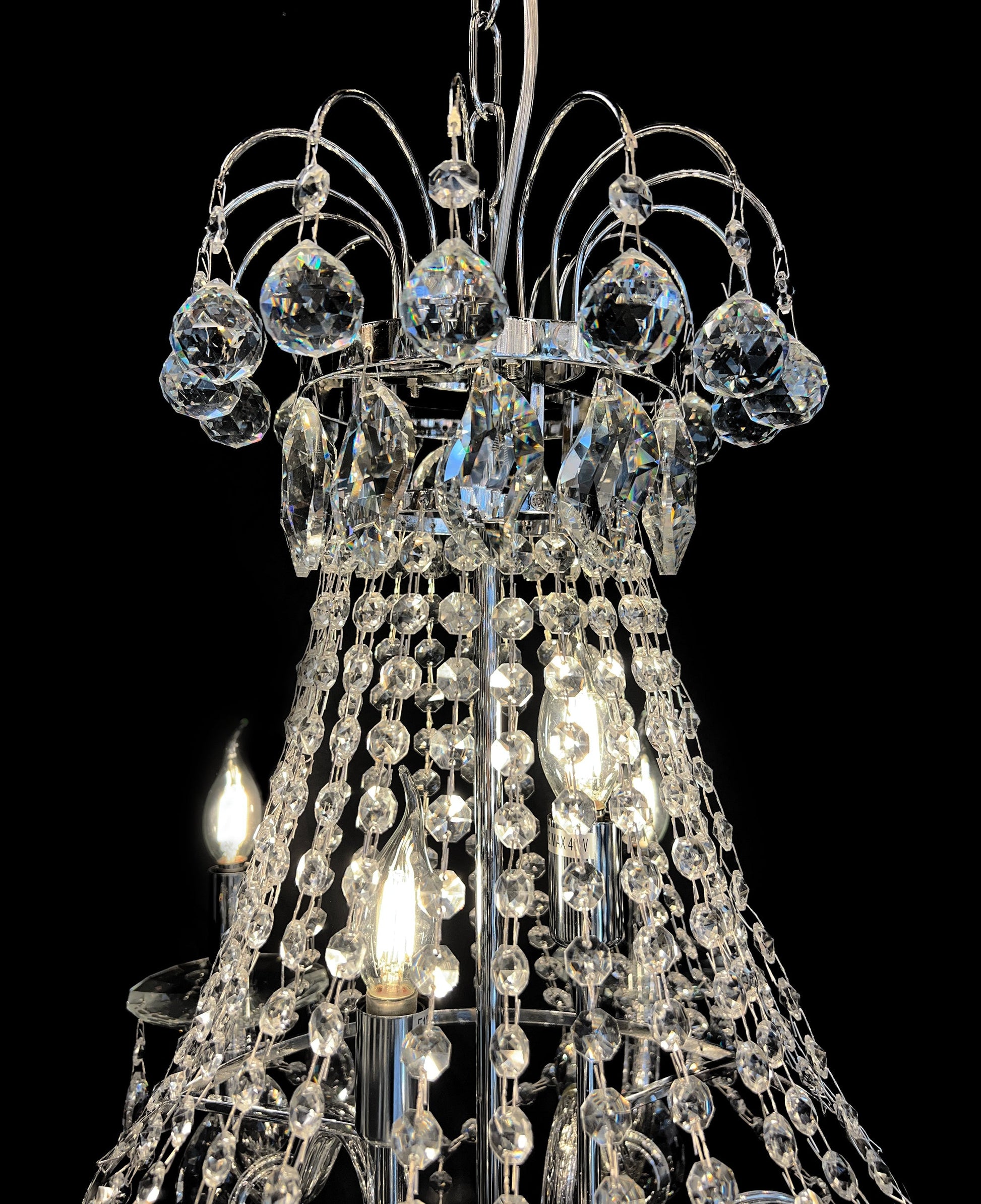 Upper section of chandelier featuring curved chrome and different size  crystal design 