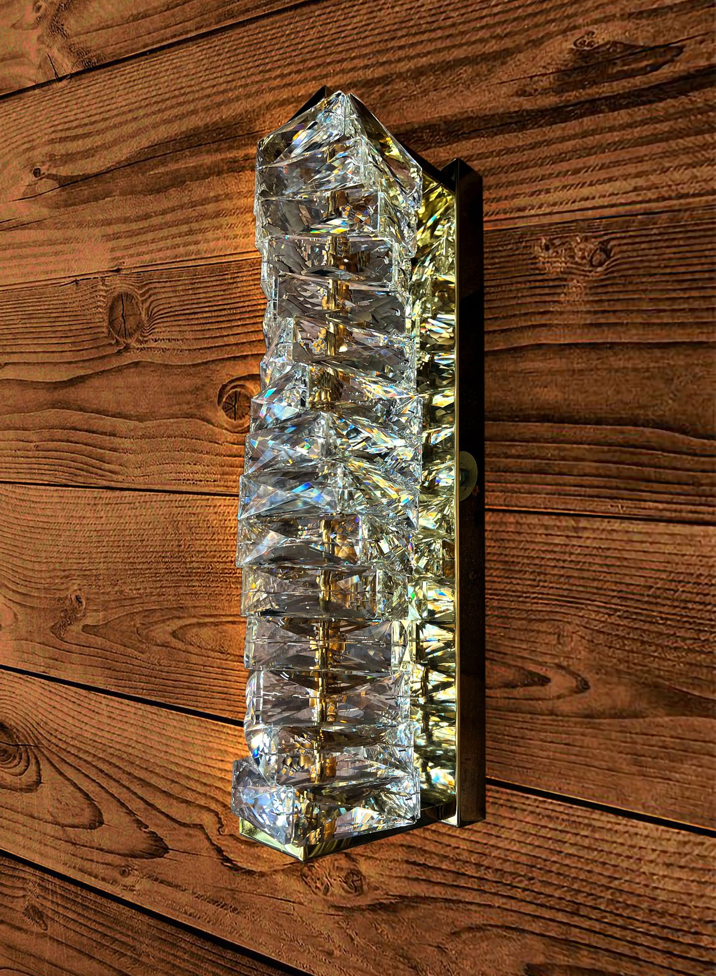 Close-up of gold crystal LED wall sconce on textured wall
