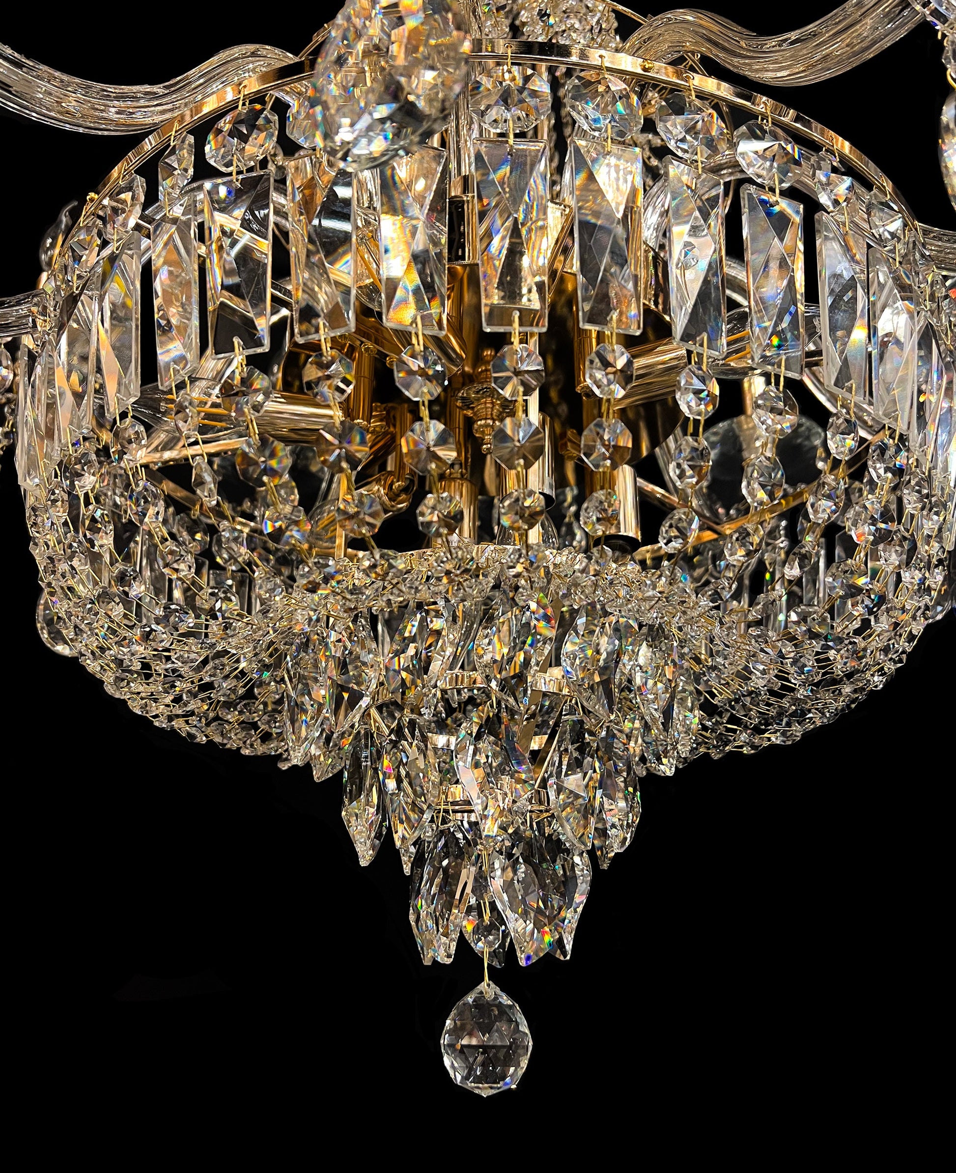 sparkly detailed gold chandelier base with clear hanging crystals reflecting warm light.