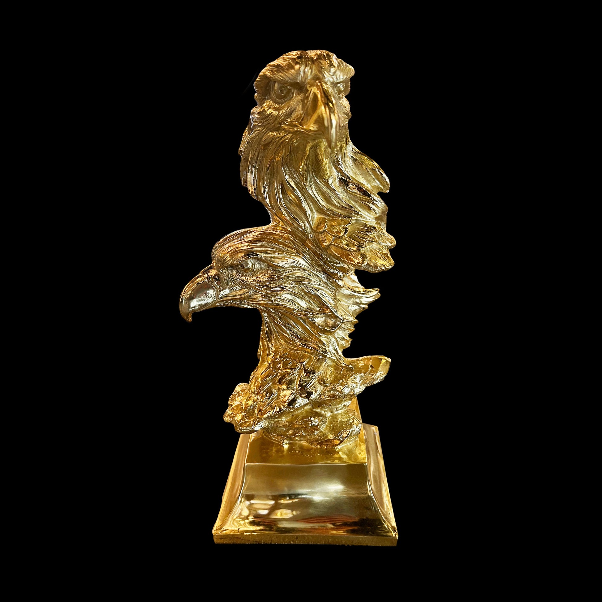 A brass gold sculpture of an American eagle with outstretched wings, standing on a square base.