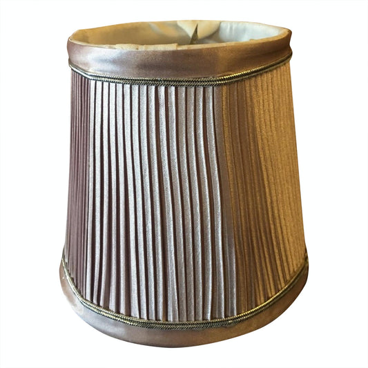 A pleated satin clip-on lamp shade in light pink, designed for use with chandeliers and other lighting fixtures.
