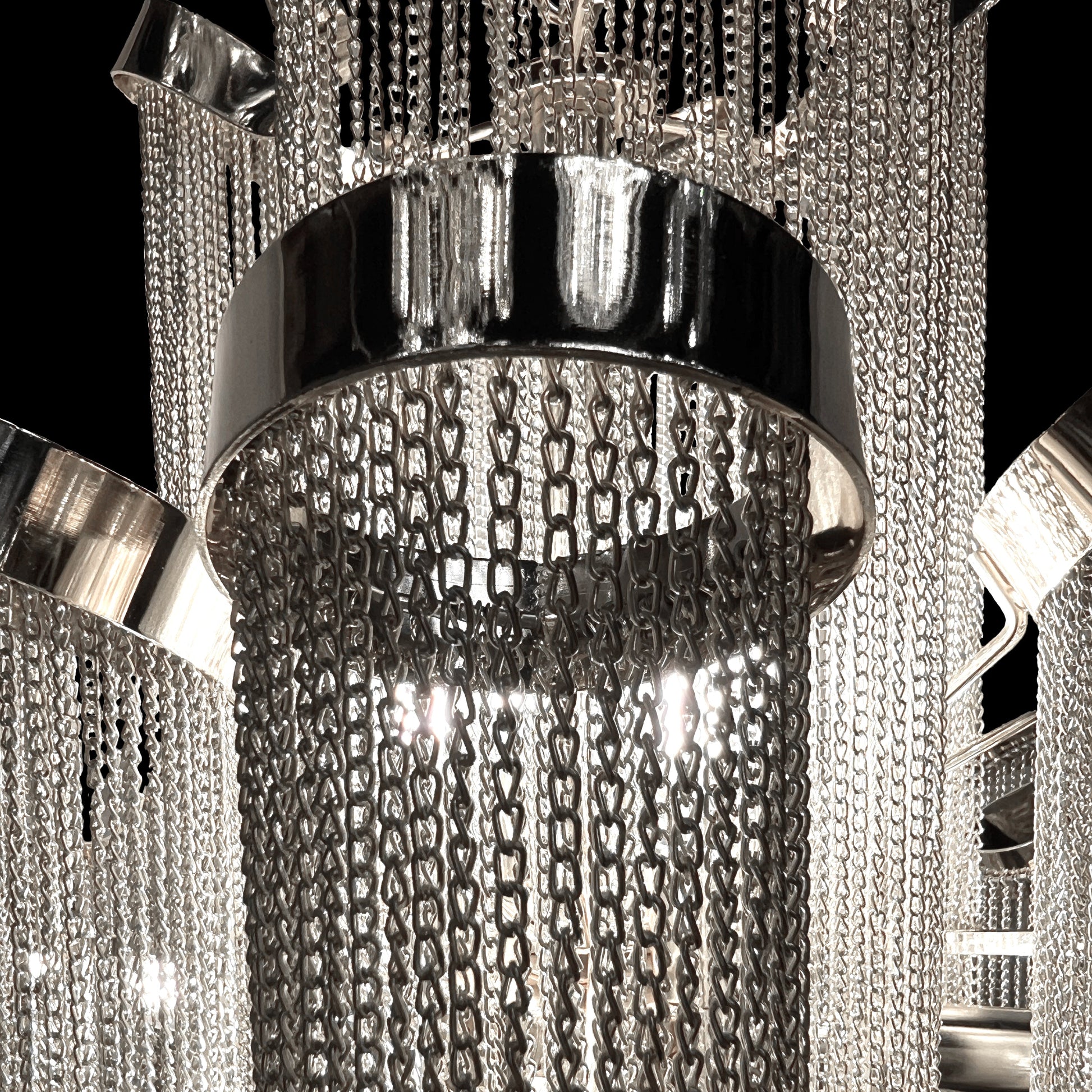 Detailed macro shot highlighting the stainless-steel frame and reflective chrome chains of the chandelier’s upper tier.
