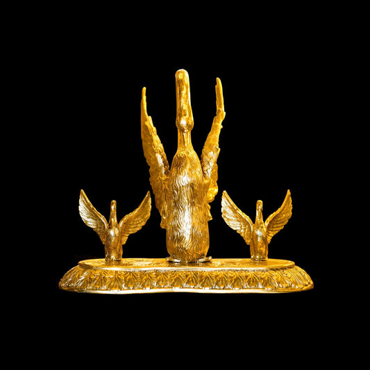 Gold statue of a hand with outstretched fingers and two winged creatures on a black background