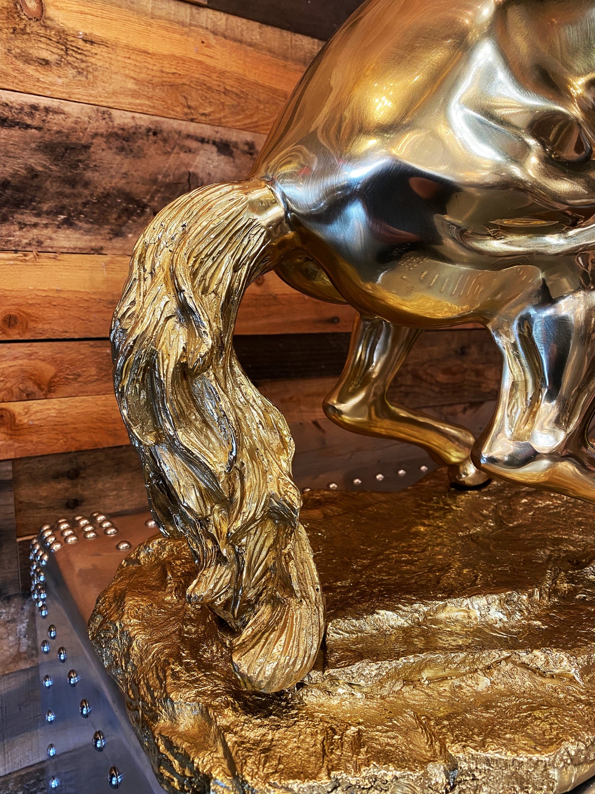 Detailed view of the muscular definition and brass texture on the back and tail of the rearing horse statue.
