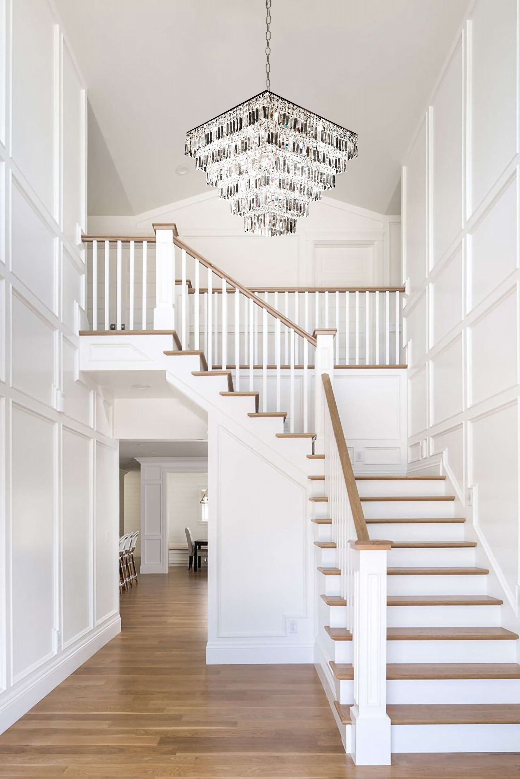 Tiered chrome crystal chandelier installed above contemporary staircase