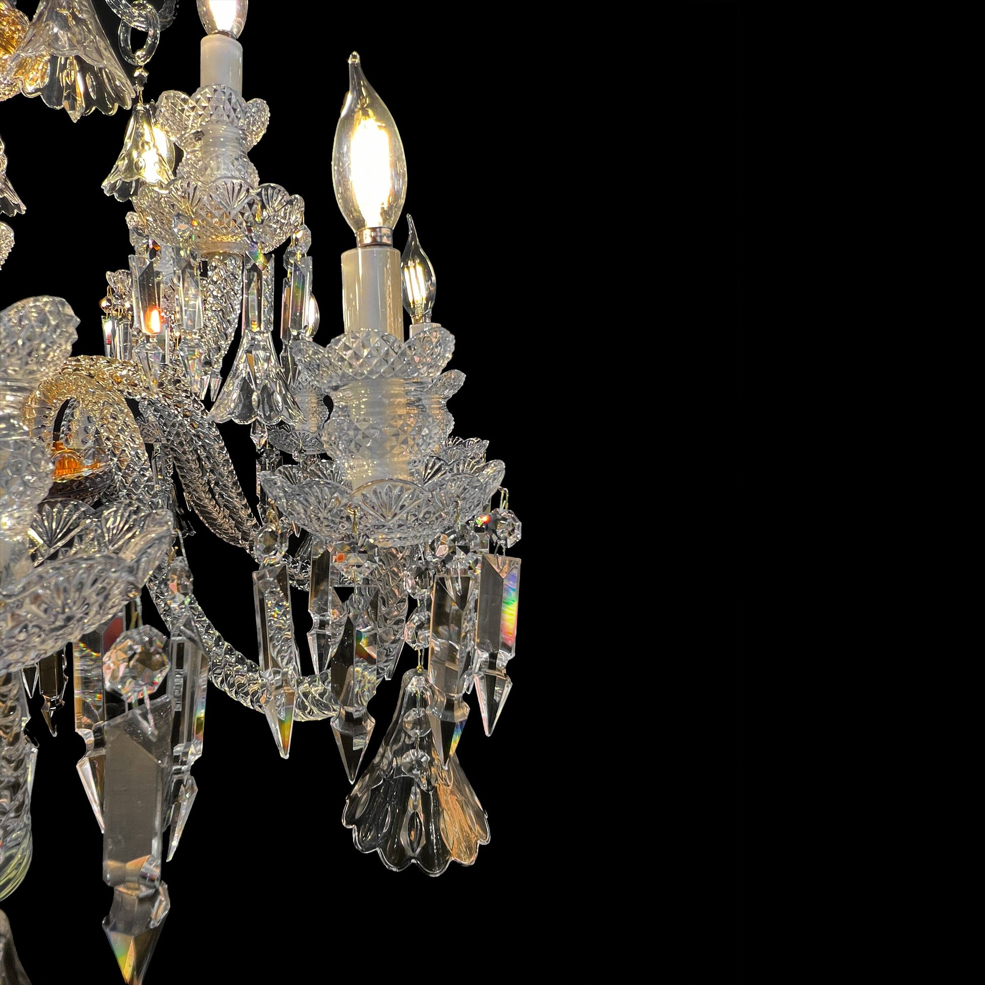 Close up view of a luxury crystal chandelier arm with gold accents and hanging crystal prisms.