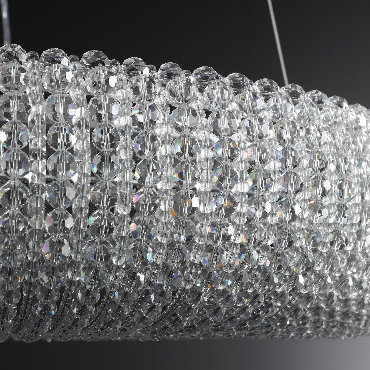 Close-up of faceted crystal beads reflecting light in a modern chandelier.