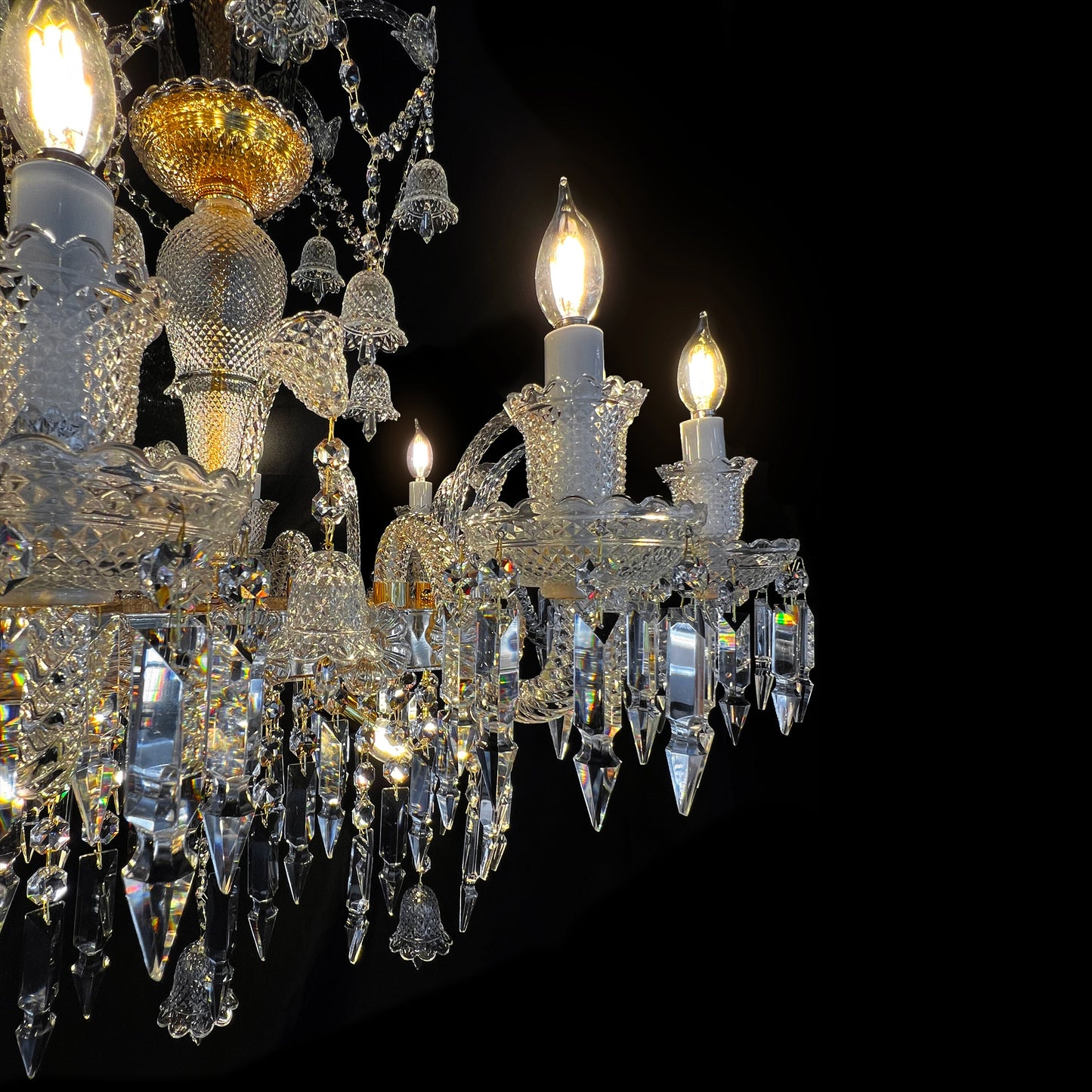 Detailed view of glass crystal drops and gold plated base of luxury Baccarat style chandelier with artisanal craftsmanship.

