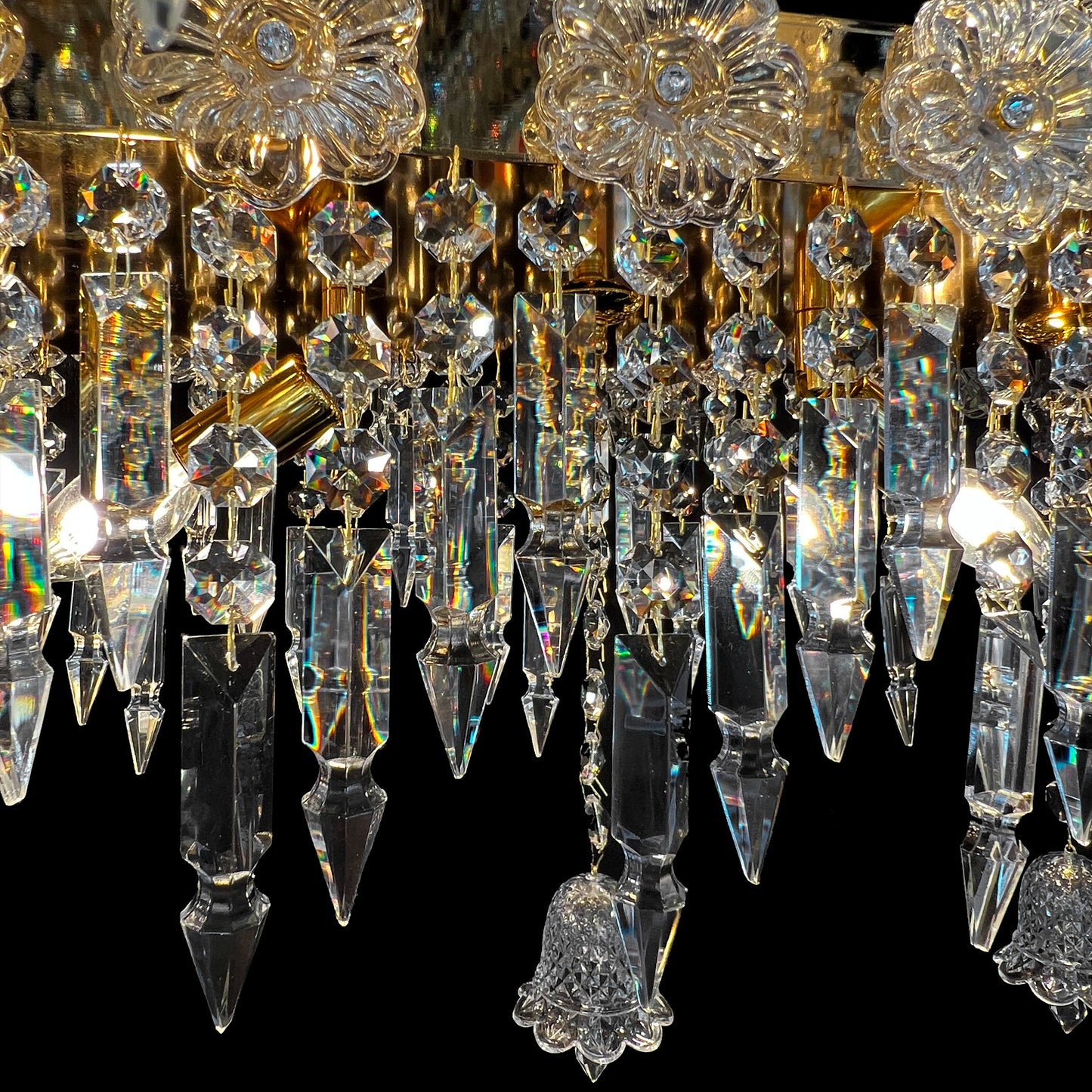 Detailed view of glass crystal drops and gold plated base of luxury Baccarat style chandelier with artisanal craftsmanship.
