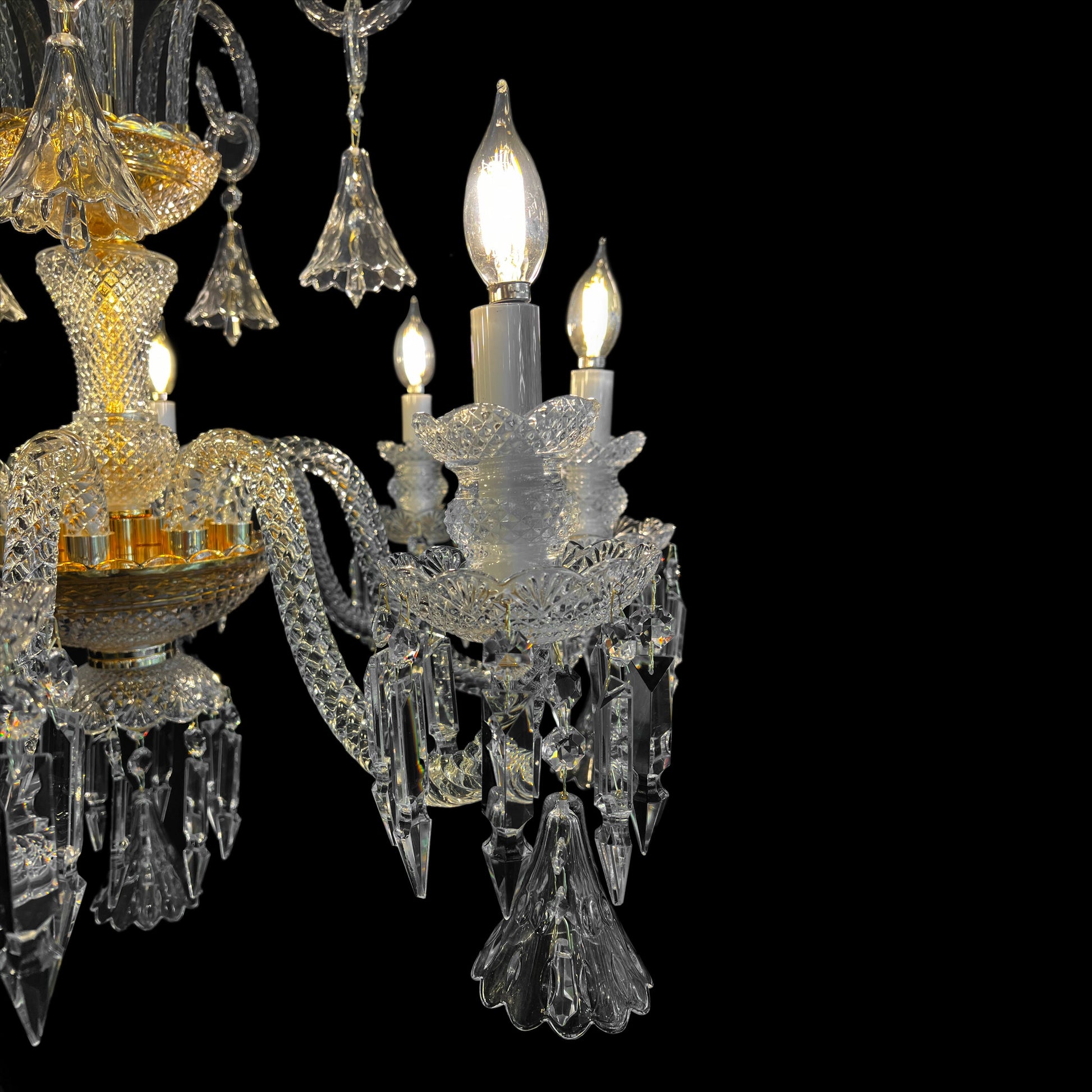 Detailed view of a gold and crystal chandelier arm featuring candle style bulbs, glass texture, and sparkling crystal drops.