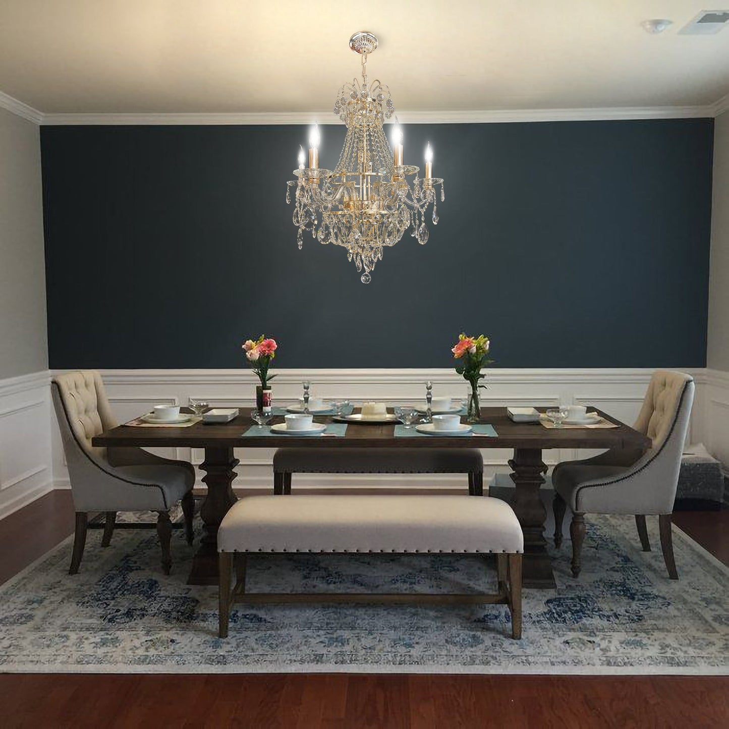 Elegant gold crystal chandelier above classic dining table with modern wall paneling.