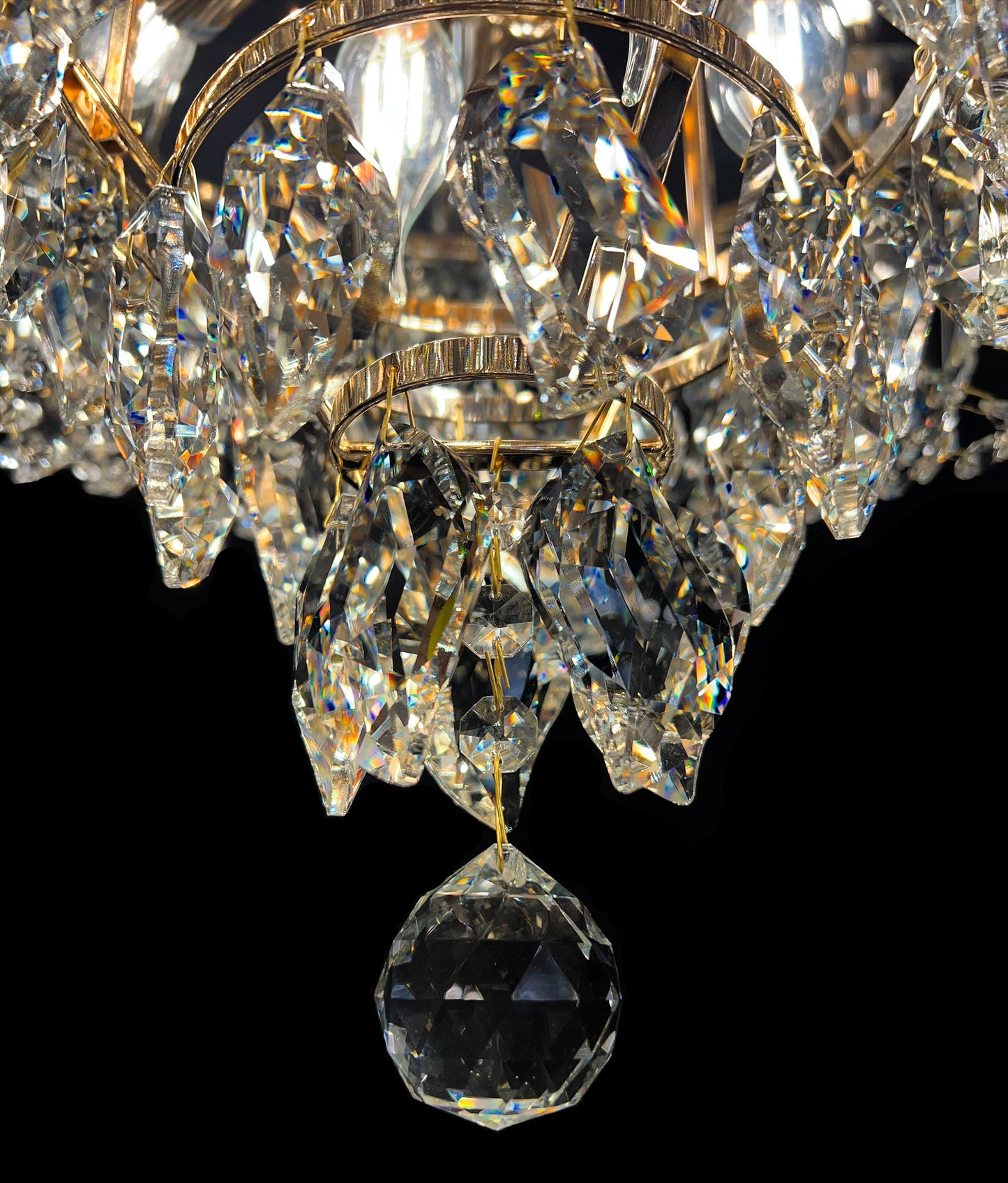 Detailed gold chandelier base with hanging crystals reflecting warm light