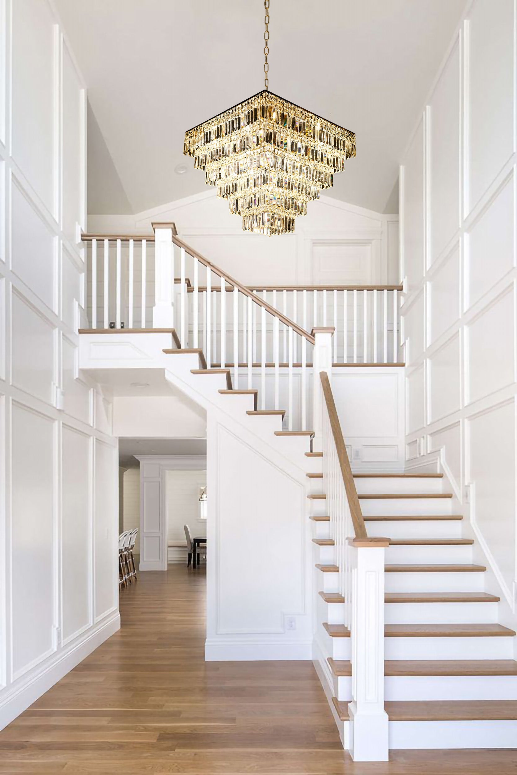 Tiered gold crystal chandelier installed above contemporary staircase