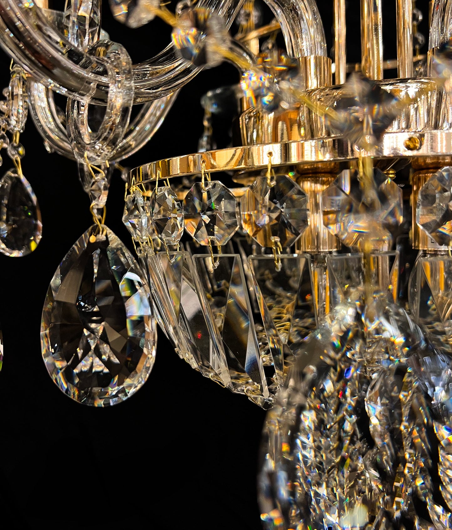 Detailed gold chandelier base with hanging crystals reflecting warm light.”