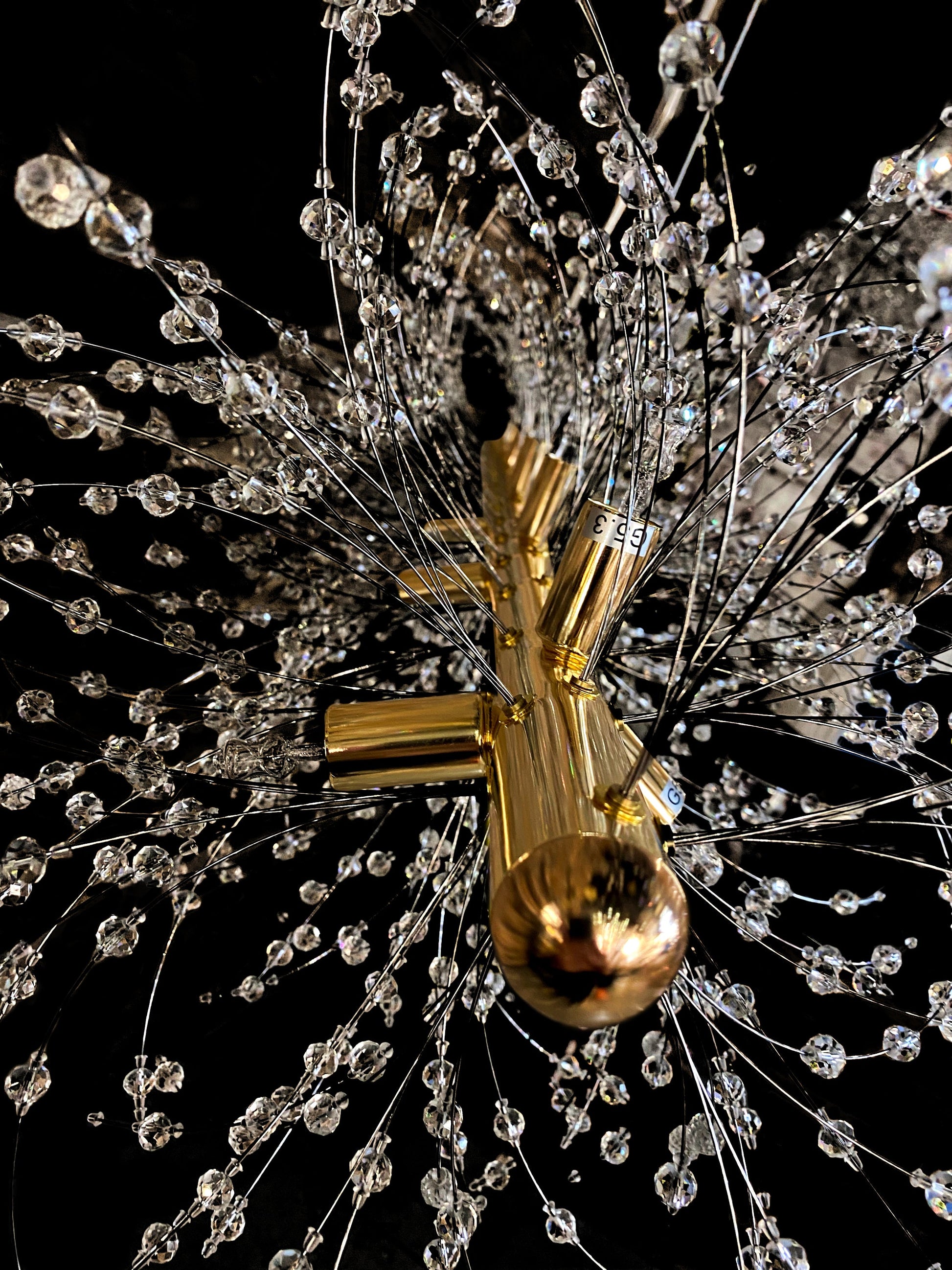 Precision-cut crystal branches detail on modern gold chandelier