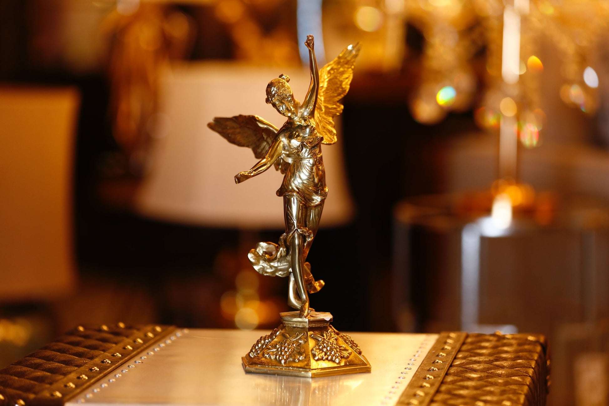 A  brass angel sculpture with intricate detailing, depicting an angel in a serene pose with outstretched wings.
