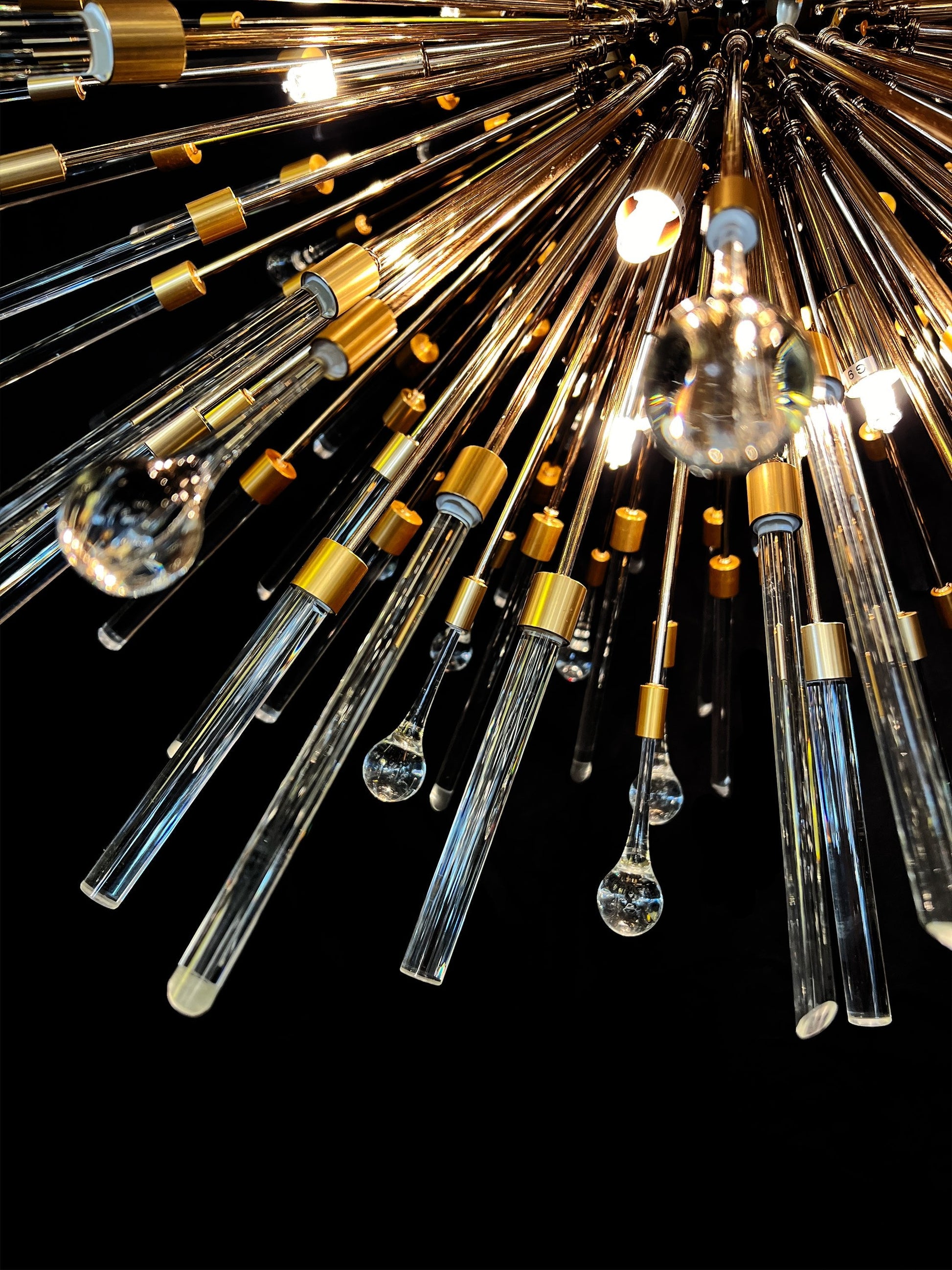 Modern pendant chandelier with gold frame and luminous glass rods.